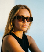 Model wearing Amara chunky geometric sunglasses in tortoise with orange lenses