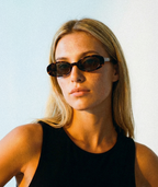 Model wearing Solene oval sunglasses in tortoise with green lenses