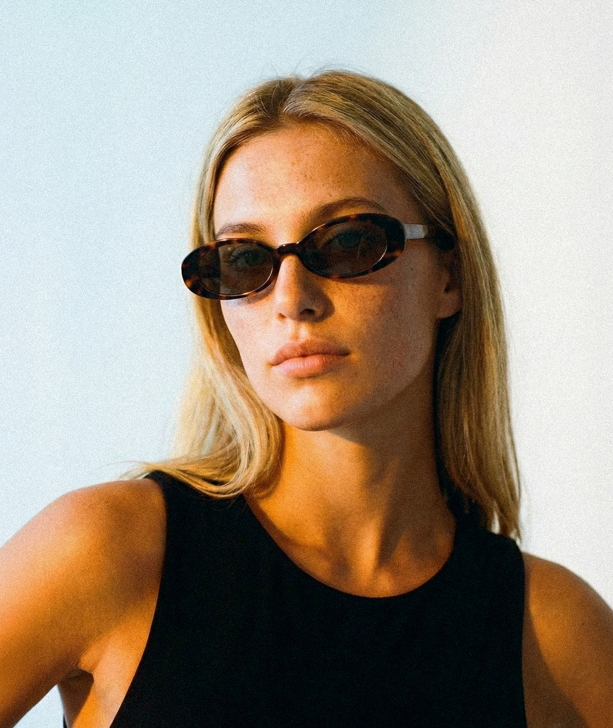 Model wearing Solene oval sunglasses in tortoise with green lenses