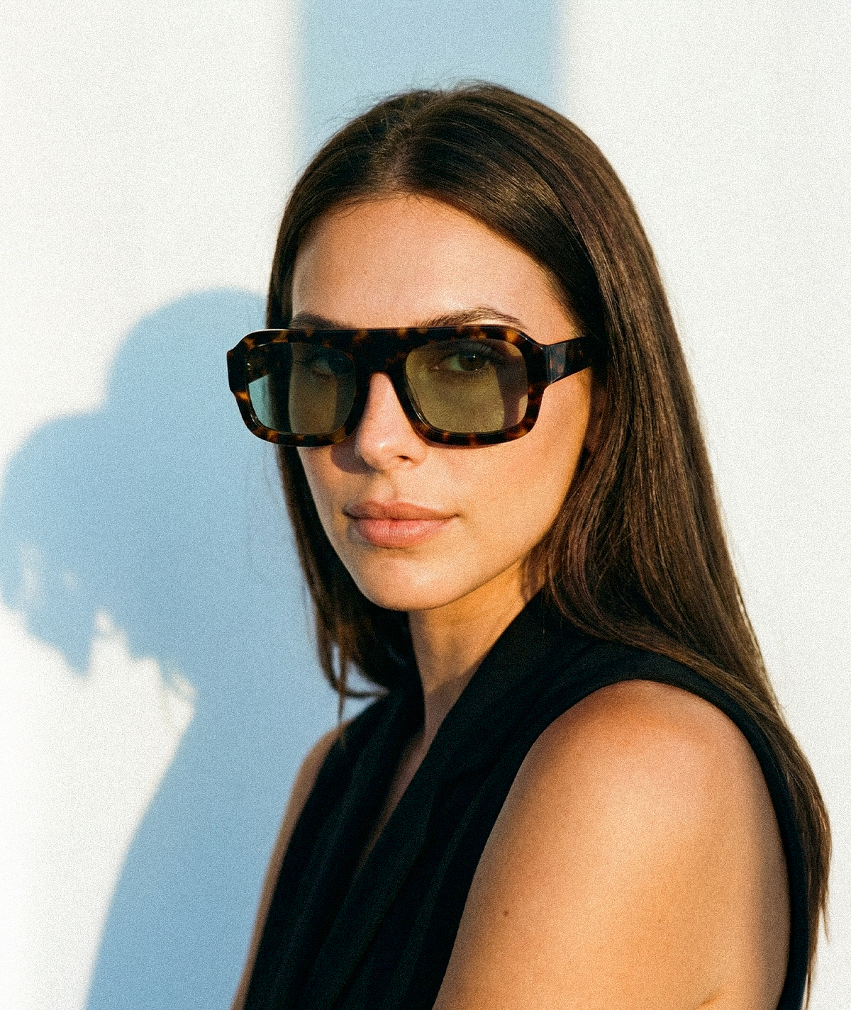 Model wearing Marlowe bold flat-top square sunglasses in tortoise with green lenses