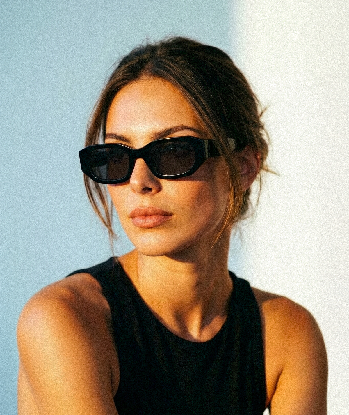 Model wearing Amara chunky geometric sunglasses in black with gray lenses