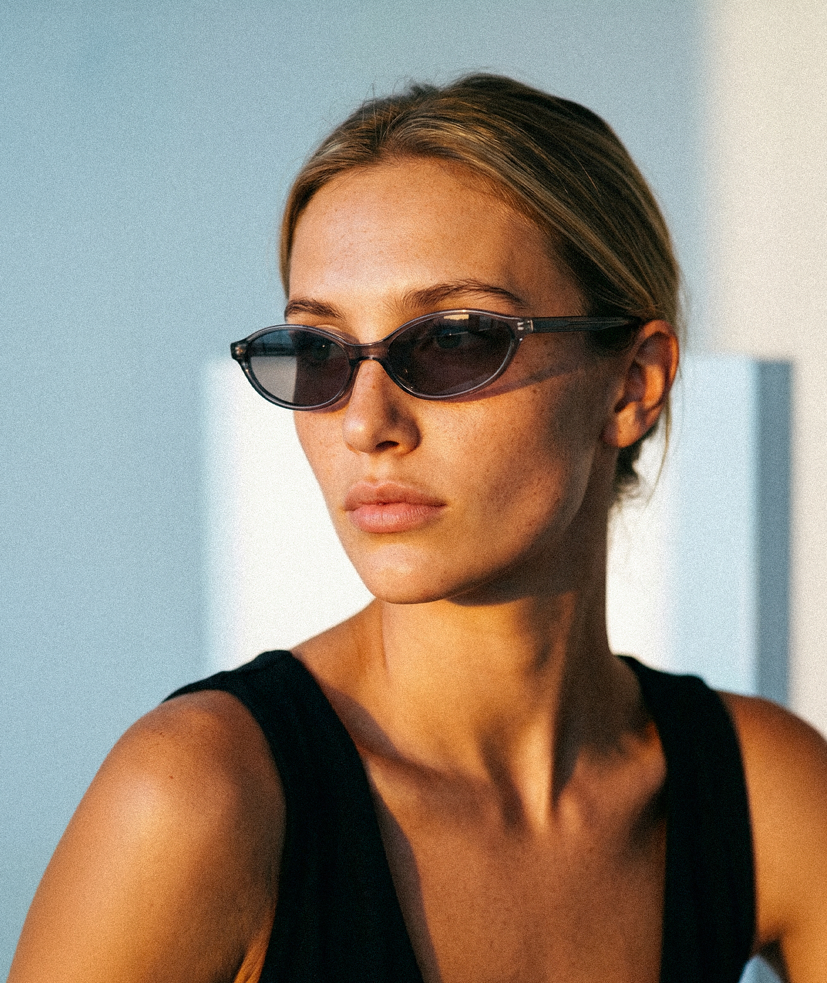 Model wearing Cleo cat-eye sunglasses in transparent gray with gray lenses
