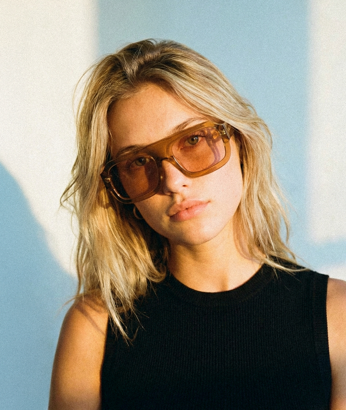 Model wearing Marlowe bold flat-top square sunglasses in transparent honey brown with amber brown lenses