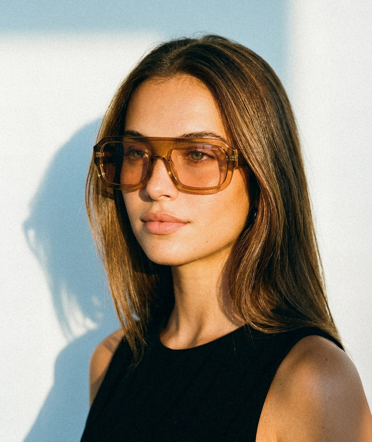Model wearing Marlowe bold flat-top square sunglasses in transparent honey brown with amber brown lenses